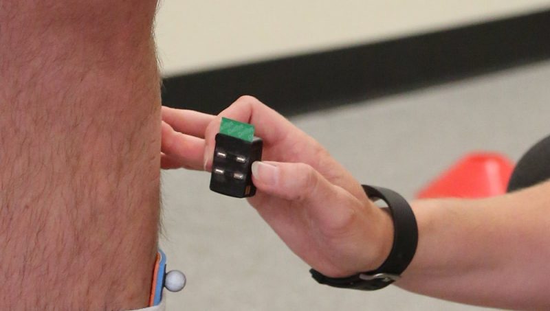 A hand palpating the back of a persons calf to place the EMG electrodes on.