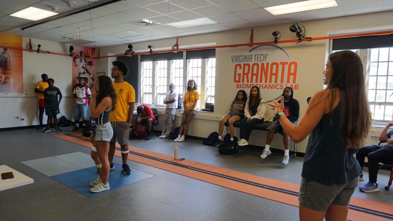 Image of a graduate student researcher speaking about biomechanics to a group of high school students in the Granata Biomechanics Lab.