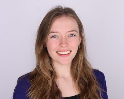 Image of Georgia Berg wearing a black shirt with a blue jacket.