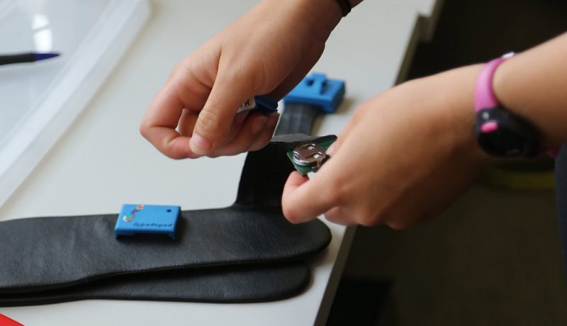 The hands of a person placing batteries into the loadsol insole sensors.